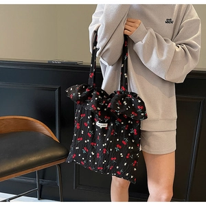 Detail of black canvas tote bag with red cherry prints and ruffled edge detailing
