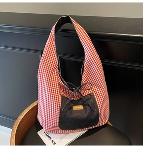 Detailed shot of red gingham tote bag featuring a denim pocket with a bow detail