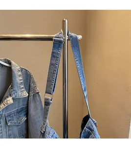 Dettaglio della fibbia in metallo regolabile e della tracolla di una borsa in denim