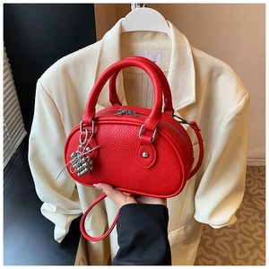 Détail du sac polochon en cuir rouge avec ferrures argentées et pendentif métallique