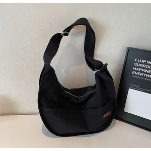 Detail of black nylon crescent crossbody bag with front pockets and adjustable strap