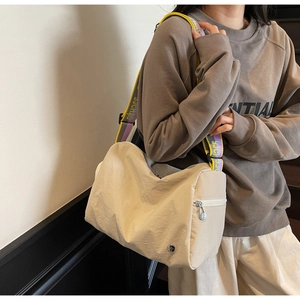 Detail of cream nylon crossbody bag featuring colorful jacquard strap and silver zipper