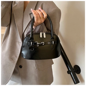 Detail view of the black glossy shell bag with silver buckles and a top handle