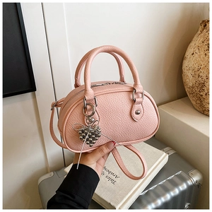 Détail du mini sac Boston rose en cuir grainé avec pendentif en forme de cœur