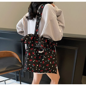 Detail of a pleated black tote bag featuring cherry prints and Magic Pocket label