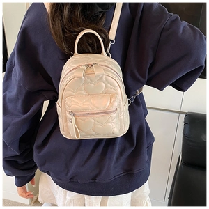 Detail of heart-quilted pearl white mini backpack on a model showing back styling