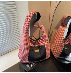 Detail of red gingham tote bag with denim front pocket and navy ribbon bow accent