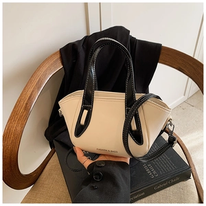Detail of cream and black contrast leather bucket bag on vintage chair background