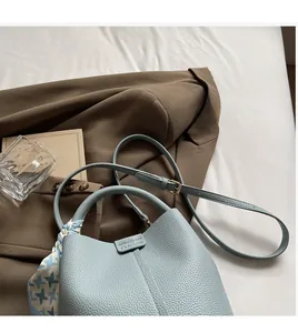 Détail d'un sac seau en cuir bleu clair grainé orné d'un foulard en soie élégant