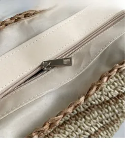 Macro detail of the smooth metal zipper and durable fabric lining on a woven straw bag