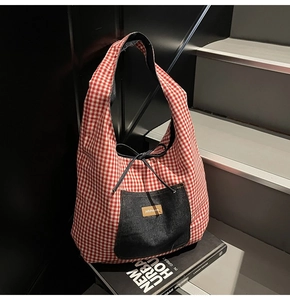Detailed view of red and white checkered tote bag with blue denim pocket and drawstrings