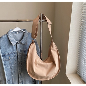 Detail of adjustable wide shoulder strap and metal buckle on khaki nylon hobo bag