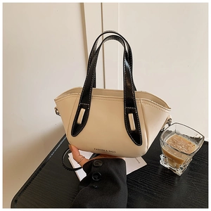 Close-up of beige leather bucket bag with black handle and silver fashion lettering