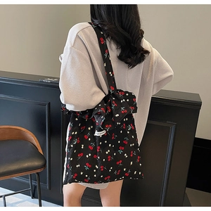 Detail of floral cherry print tote bag featuring a large decorative bow on the shoulder strap