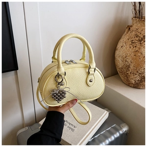 Détail du sac coquille en cuir PU jaune avec breloque cœur et texture litchi