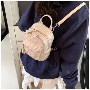 Detail of beige mini backpack featuring heart-shaped quilting and smooth PU leather finish