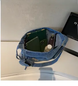 Dettaglio interno di una grande borsa tote in denim con ampio scomparto principale e oggetti