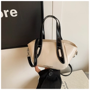 Detail of a chic cream and black mini tote bag featuring dual handles and silver hardware