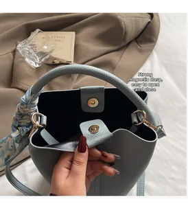 Détail du sac seau bleu clair montrant le fermoir magnétique doré et la texture du cuir