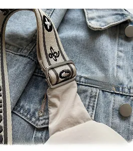 Detail of adjustable floral jacquard shoulder strap on a beige crossbody bag