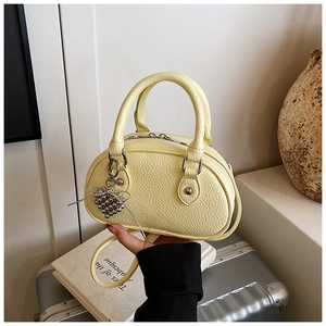 Détail du mini sac Boston jaune en cuir litchi avec breloque cœur argentée et nœud