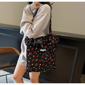 Detail of black canvas tote bag with cherry floral print and Magic Pocket label