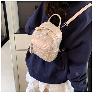 Detail showing the heart quilted pattern and bow decoration on the white mini backpack