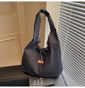 Detail of navy denim tote bag featuring drawstring closure and checkered lining