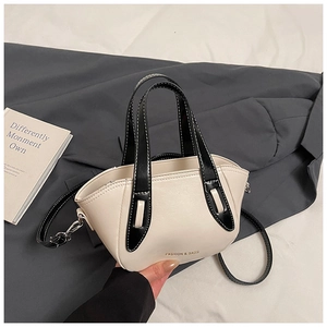 Detailed macro view of cream leather handbag with black contrast stitching and gold logo