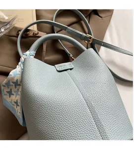 Détail du sac seau bleu clair avec texture cuir grainé et foulard en soie décoratif