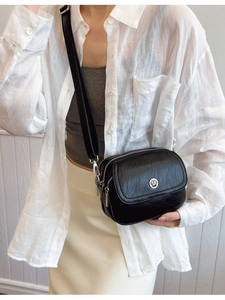 Black vegan leather crossbody bag with three zipper compartments and wide shoulder strap