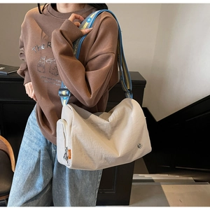 Detail of beige nylon crossbody bag featuring a wide geometric woven shoulder strap
