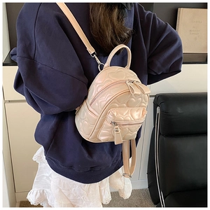Rear view of a model wearing a pearlescent pink mini backpack with heart quilted patterns