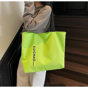Close-up of fluorescent green tote bag with black letter print and wide strap