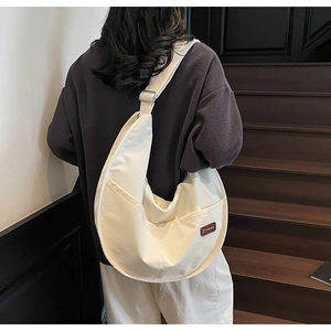 Close-up of cream nylon crossbody tote featuring a vintage side pocket and leather label