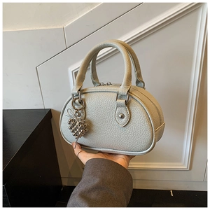Détail du mini sac polochon vert sauge clair en cuir grainé avec pendentif métallique