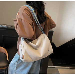 Detail of the cream-white crossbody bag with colorful woven strap and side zipper