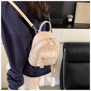 Detail view of heart-quilted ivory PU leather mini backpack worn over the shoulder