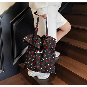 Close-up of black floral tote bag featuring red cherry prints and ruffled edge detail
