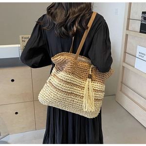 Detail of woven gradient tote bag with brown leather straps and stylish hanging tassel