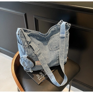 Dettaglio di borsa tote in denim blu lavato con tasche multiple e mini pochette