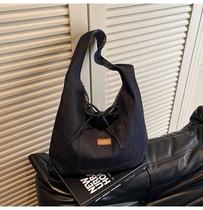 Detail of dark blue denim hobo tote with leather logo tag and checkerboard lining