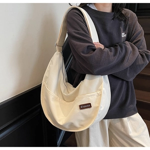 Detail of off-white crescent canvas crossbody bag featuring front pockets and wide strap