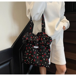 Close-up of black floral tote bag with cherry prints and decorative ruffled edge detail