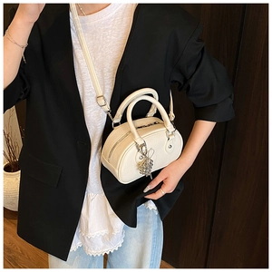 Détail du sac polochon blanc en cuir grainé avec breloque argentée et poignée supérieure