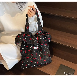 Detail of black floral tote bag with cherry prints and ruffled edges on wooden stairs
