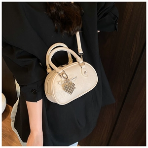 Détail d'un sac à bandoulière crème avec texture de cuir et pendentif en cœur