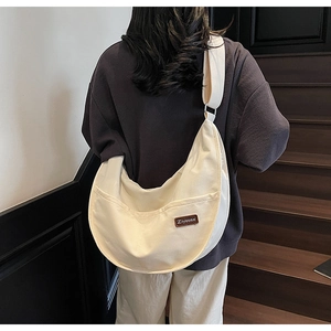 Detail of off-white nylon crescent tote with leather logo patch and silver buckle strap