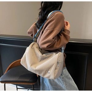 Detail of grey crossbody bag featuring a blue lettered jacquard strap and side zipper pocket