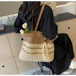 Macro detail of gradient straw tote bag featuring long tassels and brown leather strap
